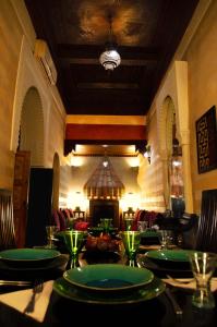 uma sala de jantar com uma mesa com placas verdes em Riad Dar Alhambra em Marrakech