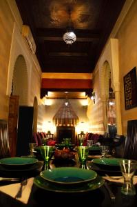 een eetkamer met een tafel met groene borden bij Riad Dar Alhambra in Marrakesh