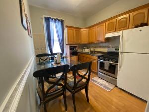Charming and cozy apartment in New Jersey close to all the fun 10 minutes to NYC في ويست نيويورك: مطبخ مع طاولة وكرسيين وثلاجة