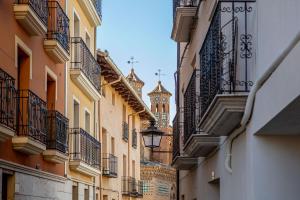 a narrow street with a clock tower in the distance at Apartamentos Hartzenbusch in Teruel