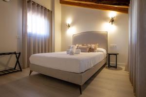 1 dormitorio con 1 cama grande con sábanas y almohadas blancas en Apartamentos Hartzenbusch, en Teruel