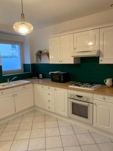 a kitchen with white cabinets and a stove top oven at Agréable maison meublée in Cherbourg en Cotentin