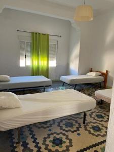 a room with three beds and a green curtain at UIM Mediterraneo Pablo Iglesias Wifi in Puerto de Sagunto