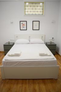1 cama blanca en una habitación con 2 mesas en Parthenon retreat, en Atenas