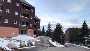 un edificio con nieve en el suelo junto a una calle en Les aiguilles d'or, en L'Alpe-d'Huez
