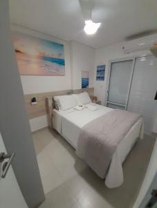 um quarto com uma cama branca e uma janela em Pe na areia Flat Unita 177 na Praia Grande