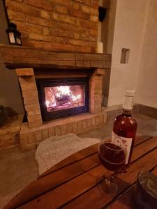 a bottle of wine and a glass on a table in front of a fireplace at Chata pod smrečkami s krbom a krásnym prostredím in Ždiar