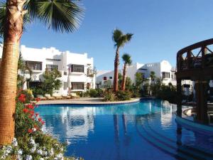 a large swimming pool with palm trees and buildings at SharmStar in Sharm El Sheikh