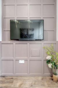 Bright & Modern 2-Bed Notting Hill Apartment في لندن: تلفزيون بشاشة مسطحة جالس على جدار أبيض