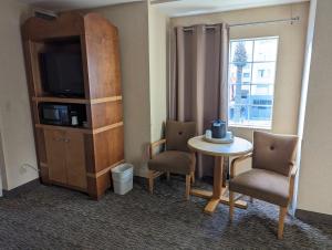 Habitación con mesa, sillas y TV. en Portofino Inn and Suites Anaheim Hotel en Anaheim