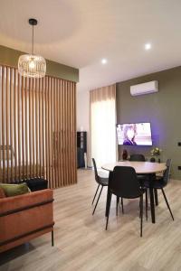 Una sala de estar con una mesa y sillas y un televisor. en La Casa di Gadu, en Casalnuovo di Napoli