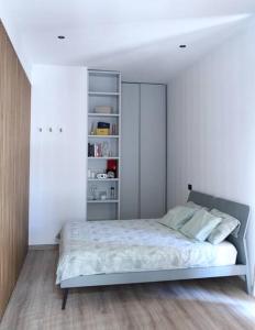 Dormitorio blanco con cama y estante de libros en La Casa di Gadu, en Casalnuovo di Napoli