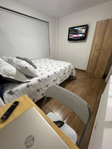 um pequeno quarto com uma cama e uma televisão em APARTAMENTO PRIVADO cerca al aeropuerto em Bogotá