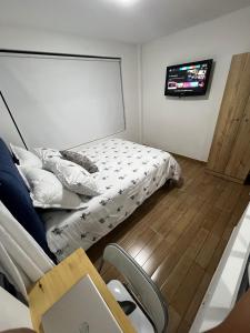 um quarto com uma cama e uma televisão na parede em APARTAMENTO PRIVADO cerca al aeropuerto em Bogotá