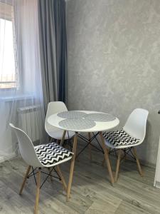 Una mesa y cuatro sillas en una habitación en 1-КОМНАТНАЯ КВАРТИРА ЕВРО В НОВОСТРОЙКЕ en Petropavlovsk