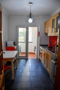une cuisine avec une table et une cuisine avec des chaises rouges dans l'établissement Tranquility Apartment, à Caniço