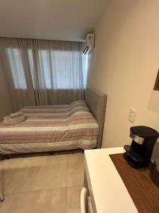 a small bedroom with a bed and a window at Flat América Campos Pelinca in Campos dos Goytacazes