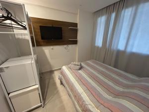 een kleine slaapkamer met een bed en een televisie bij Flat América Campos Pelinca in Campos dos Goytacazes