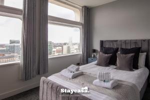 a bedroom with a large bed with two towels at Luxury 2bdr Penthouse On 23rd Floor With View in Manchester