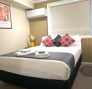 a bedroom with a large bed with colorful pillows at Comfort Inn Serenity Bathurst in Bathurst