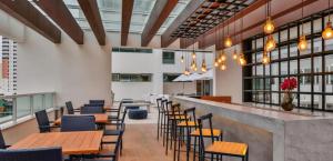 ein Restaurant mit Holztischen und -stühlen und Fenstern in der Unterkunft Flat encantador América Campos in Campos dos Goytacazes