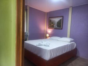 Dormitorio púrpura con cama con sábanas blancas en Casa Rural Aralia, en Fortuna