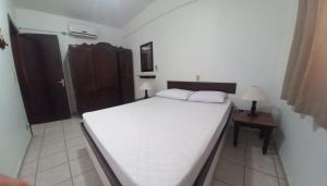 a bedroom with a large white bed and a table at Edificio Daniela Ap 101 in Bombinhas