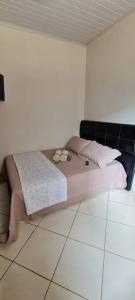 uma cama num quarto branco com almofadas cor-de-rosa em Rose House em Arraial do Cabo