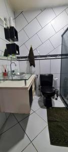 a bathroom with a black toilet and a sink at Rose House in Arraial do Cabo