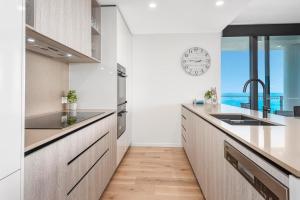 a kitchen with white cabinets and a counter with a sink at Breathtaking Burleigh Beach Abode in Gold Coast