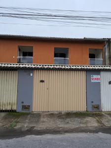 um edifício com duas portas de garagem e duas janelas em Casa aconchego Parque Mambucaba em Angra dos Reis