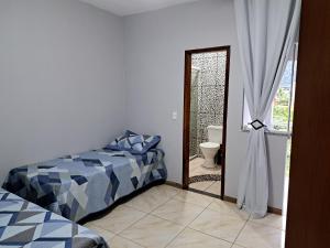 um quarto com uma cama e uma porta para uma casa de banho em Casa aconchego Parque Mambucaba em Angra dos Reis