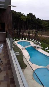 two swimming pools with lounge chairs in a resort at depto pinamar in Pinamar