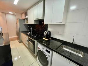 een keuken met witte kasten en een wasmachine bij Apartamento Canto do Forte - PG in Praia Grande