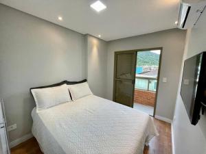 a bedroom with a bed and a television in it at Apartamento no Canto do Forte - Praia Grande in Praia Grande