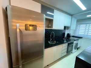 a stainless steel refrigerator in a kitchen with black counter tops at Apartamento no Canto do Forte - Praia Grande in Praia Grande