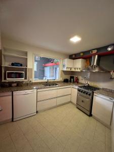 a large kitchen with white cabinets and a window at De norte a sur in Puerto Madryn