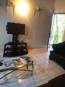 ein Wohnzimmer mit einem TV und einem Couchtisch in der Unterkunft Aquamarine Ave in Montego Bay