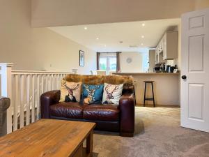 a brown leather couch in a living room with a table at The Hideaway in Chapel en le Frith