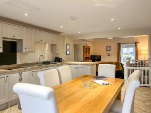 a kitchen with a wooden table and white chairs at The Hideaway in Chapel en le Frith