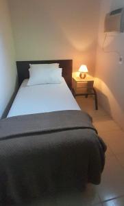 a bedroom with a bed and a night stand with a lamp at Chalé Brisas do Rio in Petrolina