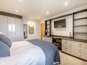 een slaapkamer met een bed, een bureau en een televisie bij Foremans Cottage in Skidby