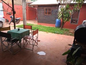 eine Terrasse mit einem Tisch und Stühlen sowie ein Haus in der Unterkunft La casa de Tilili in Puerto Iguazú