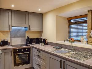 a kitchen with white cabinets and a sink at Little Jacks Cottage in Todmorden