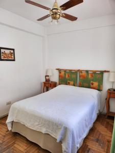 1 dormitorio con 1 cama blanca y ventilador de techo en Departamento Falucho en Mar del Plata
