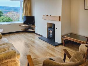 a living room with a fireplace and a tv at Barr Beithe Upper in Dalavich