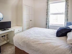 a bedroom with a bed and a desk with a television at Macdonald House in Dornoch