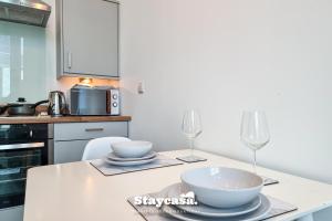 een keuken met een tafel met twee wijnglazen bij Spacious Central Apartment With Great Transports in Stockport
