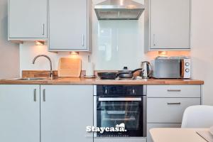 een keuken met witte kasten en een zwarte oven bij Spacious Central Apartment With Great Transports in Stockport