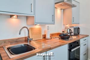 a kitchen with a sink and a microwave at Spacious Central Apartment With Great Transports in Stockport